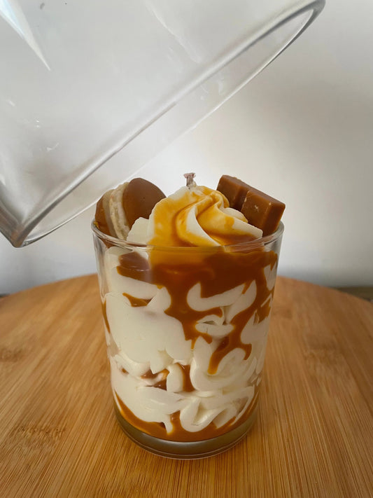 Bougie artisanale parfumée caramel façon dessert, présentée sur un plateau en bois.