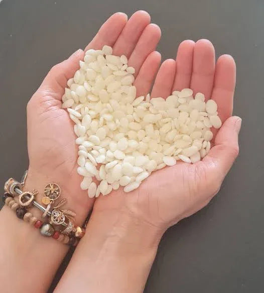 Mains tenant des copeaux de cire en forme de cœur, création bougie artisanale française